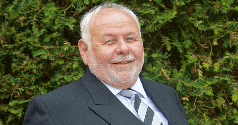 Tony Mears in black suit looking forward