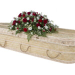 The Bamboo Woven Coffin with red and white roses, white daisies and greenery spray on top