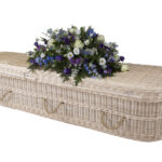 The Cane Coffin with large purple, blue and white flower spray on top