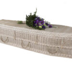 The Cane Coffin with purple and white flower bouquet on top