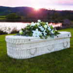 The Cane Coffin with large white lillie and white rose flower spray on top