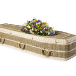 The Pandanus Coffin with mixed flower spray on top in white, yellow, pink and purple