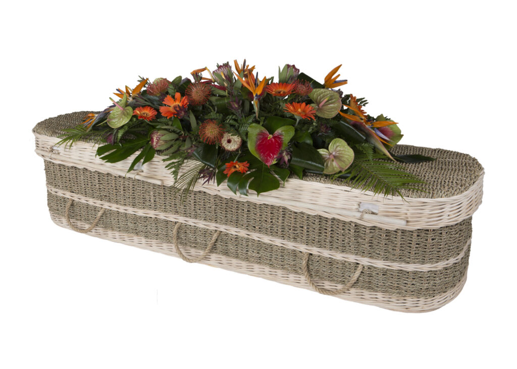 The Seagrass Coffin with large mixed orange flower spray on top