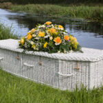 The Somerset Willow Colours Coffin in white with mixed yellow flower spray on top