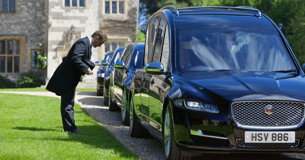 Funeral Director bowing at the side of a hearse