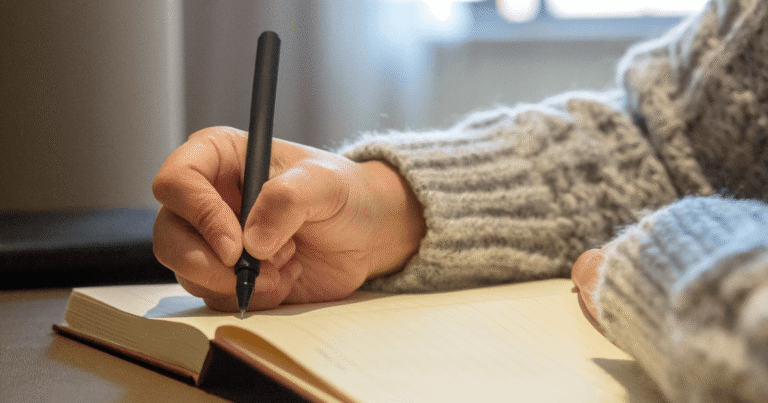 Close up of a hand writing with a pen in a notebook