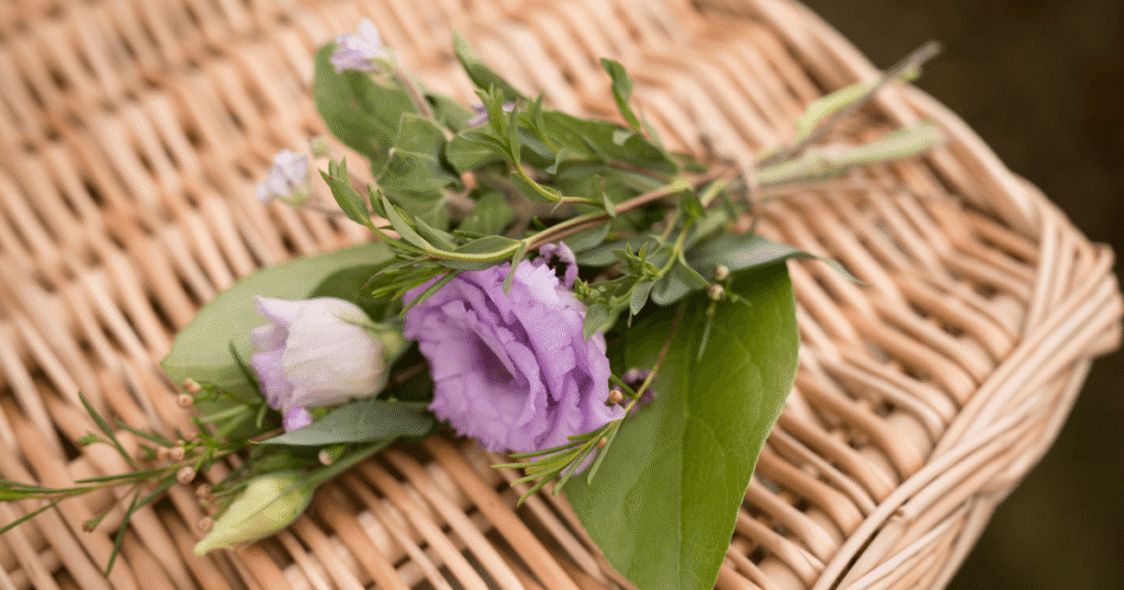 Wicker coffin with purple flowers and greenery on top